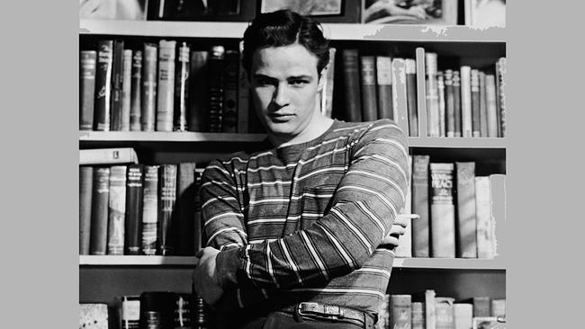 Schauspieler und Filmlegende Marlon Brando steht vor einem Bücherregal