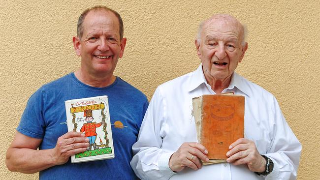 © ORF Mario Merl und Vater Harry Merl stehen vor einer hellen beigen Wand und halten jeweils ein Buch in den Händen