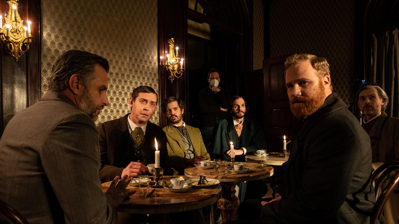 Sechs Männer sitzen in einem Cafe