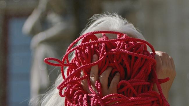 Frau hält rotes Seilknäuel vors Gesicht