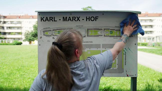 Frau putzt Schild: Karl Marx Hof