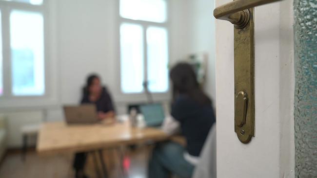offene Tür, dahinter Menschen am Computer