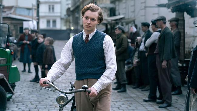 © DOR FILM/Petro Domenigg/Alamode Film Filmstill "Bruno" - junger Mann mit Hemd, Pollunder und Krawatte mit Fahrrad auf der Straße