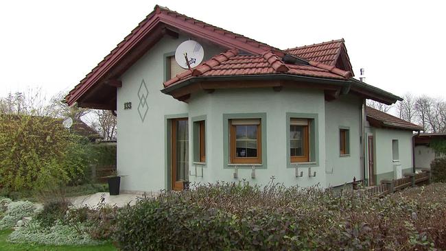ein Kleingartenhaus von aussen mit einem Roten Ziegeldach und grüner Wandfarbe