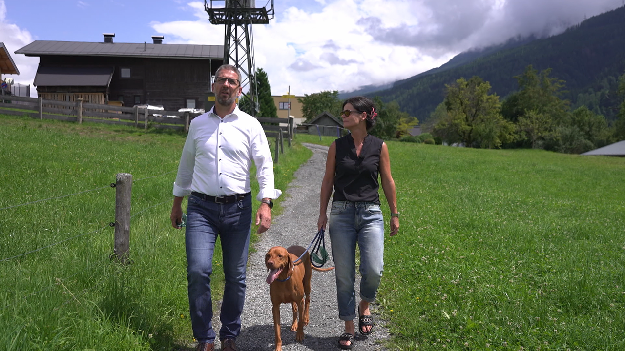 Das Ehepaar ist beim Spaziergang mit dem angeleinten Hund zu sehen