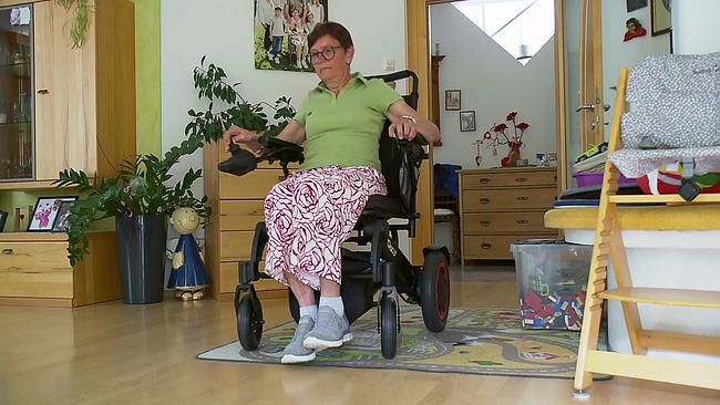 Die schwer erkrankte Frau im Rollstuhl sitzend ist zu sehen