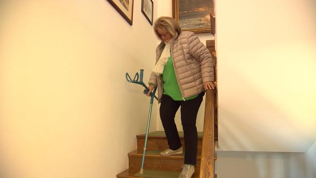 Die Pensionistin ist zu sehen, wie sie mit Krücken mühsam die Stufen runter steigt