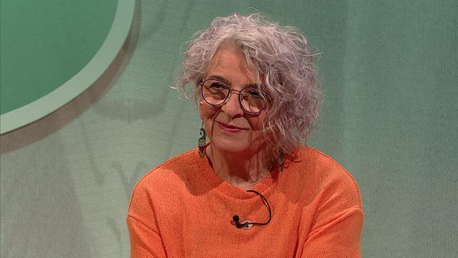 Angelika, Mitarbeiterin einer Glas-Kunstwerkstätte in Pension, graue, gewellte Haare, Brille, orangefarbener Pullover