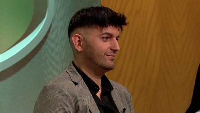 Kevin, Krankenpfleger in Ausbildung, schwarze, kurze Haare, leichter Bart, schwarz-weißes Sakko mit Karomuster