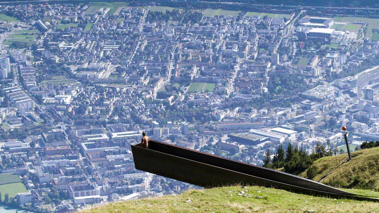 Hanno Settele blickt von einer Aussichtsplattform aus, auf die mit Häusern zugepflasterte Stadt Innsbruck. 