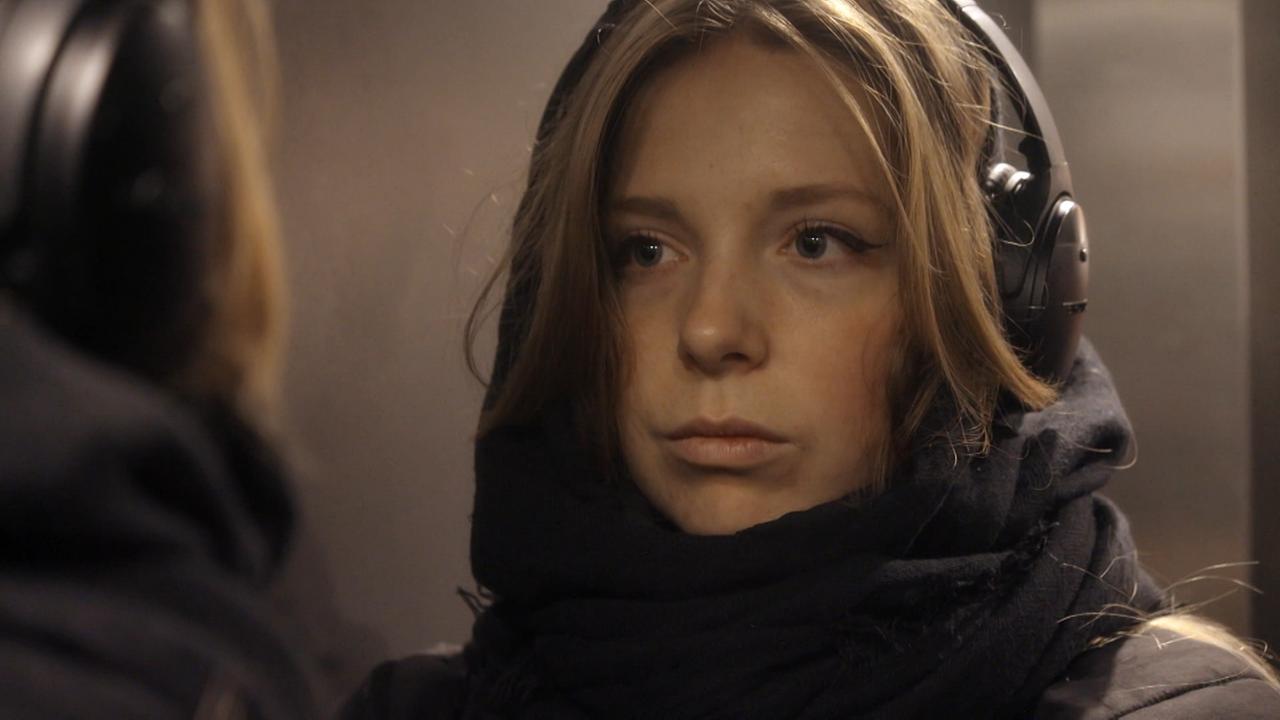 © VPRO/ORF Die Modeschöpferin Amber Jae Slooten mit Jacke bekleidet und Kopfhörern am Haupt blickt in den Spiegel.