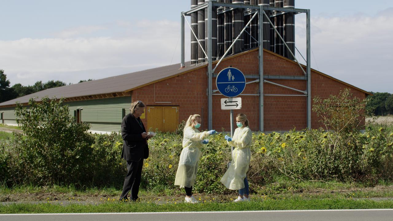 Der deutsche Nephrologe Gerd-Ludwig Meyer und zwei Kolleginnen in Schutzkleidung nehmen vor einem Hühnermastbetrieb Proben.