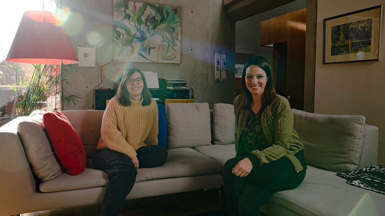 Kathi Vass und Lisa Gadenstätter sitzen auf einem Sofa und schauen in die Kamera.
