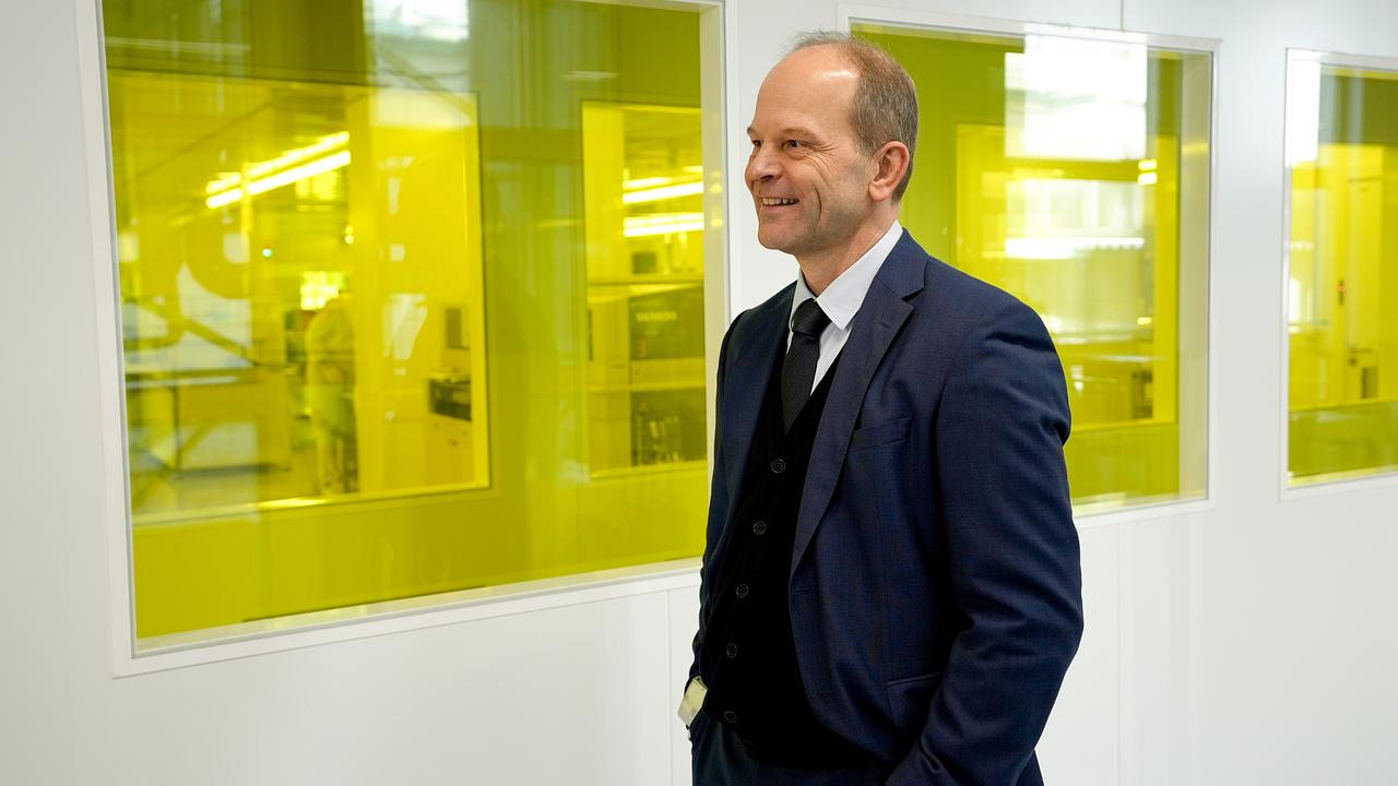 Andreas Gerstenmayer steht lachend vor gelben Plexiglasfenstern in seinem Werk.