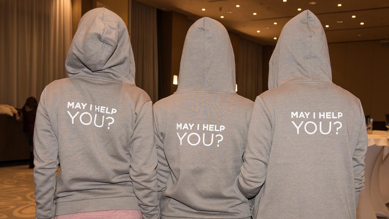 © ORF/Graph Art Line e.U. Drei Personen von hinten, auf ihren Hoodies die Aufschrift "May I Help You?"