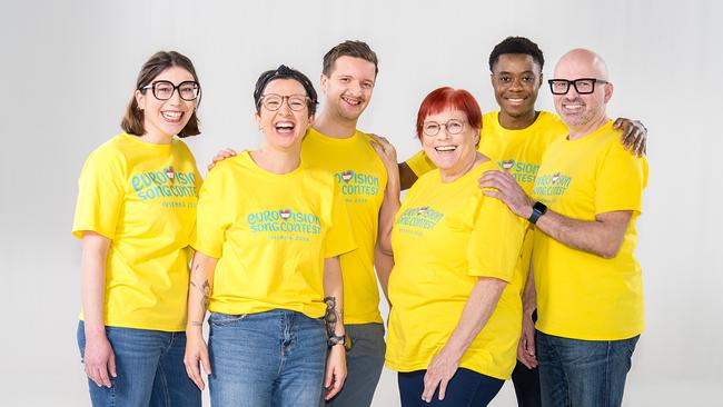 Mehrere Volunteers mit gelben T-Shirts mit der Aufschrift „Eurovision Song Contest“ strahlen freundlich in die Kamera