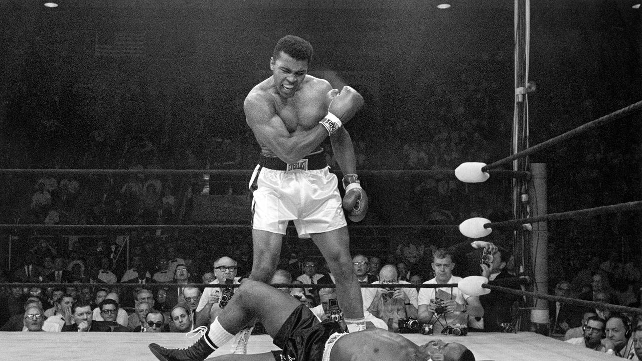 Im Bild: Der Schwergewichts-Champion Muhammad Ali steht über dem gefallenen Herausforderer Sonny Liston und schreit und gestikuliert, kurz nachdem er Liston am 25. Mai 1965 in Lewiston, Maine, mit einem kurzen, harten Schlag auf den Kiefer zu Boden geworfen hat. Der Kampf dauerte in der ersten Runde nur eine Minute. Ali ist der einzige Mann, der jemals dreimal die Weltmeisterschaft im Schwergewichtsboxen gewonnen hat. Außerdem gewann er bei den Olympischen Sommerspielen 1960 in Rom als Mitglied der US-amerikanischen olympischen Boxmannschaft eine Goldmedaille im Halbschwergewicht. 1964 ließ er den Namen Cassius Clay fallen und nahm den muslimischen Namen Muhammad Ali an.