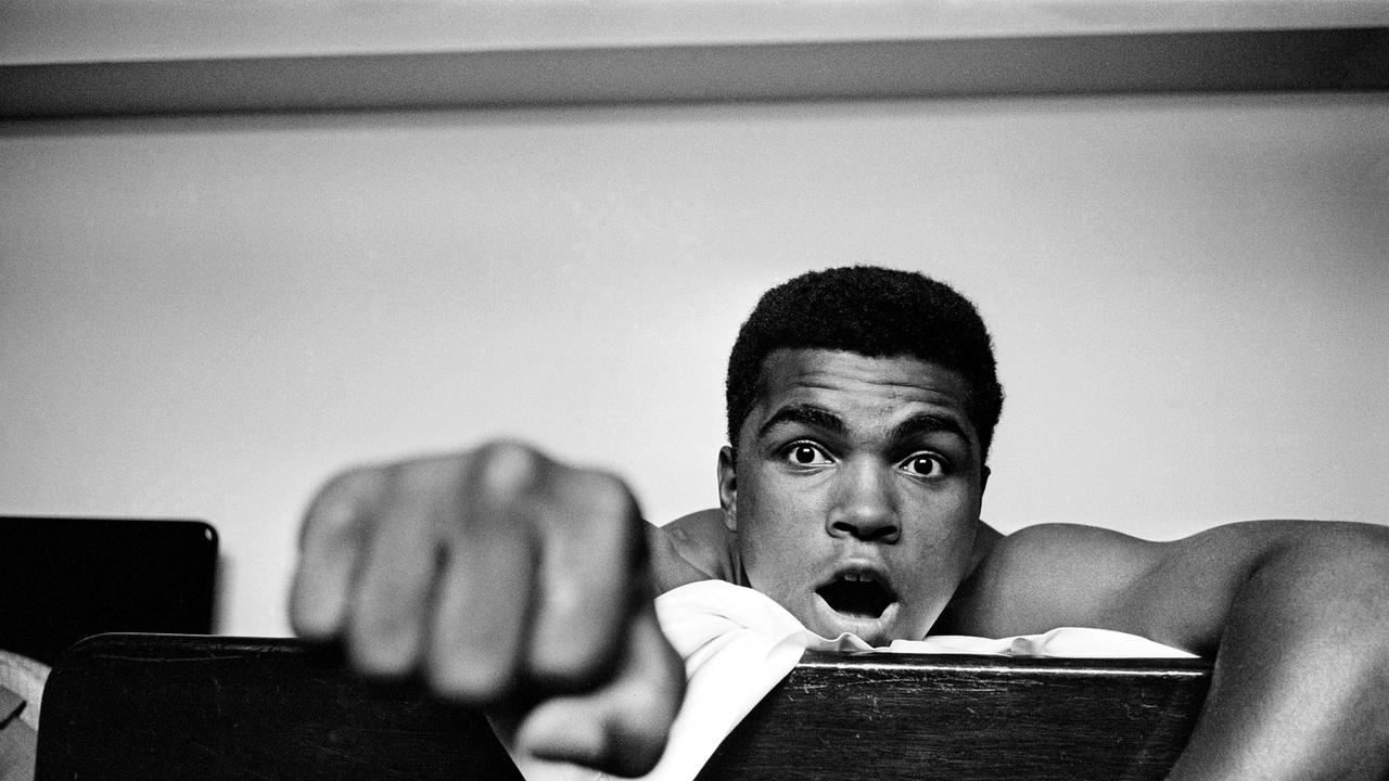 Im Bild: Der amerikanische Schwergewichtsboxer Cassius Clay (später Muhammad Ali, 1942 – 2016) macht eine Faust, während er auf seinem Hotelbett liegt, London, 27. Mai 1963. Clay ist am 18. Juni in London für ein Kampf gegen Henry Cooper.