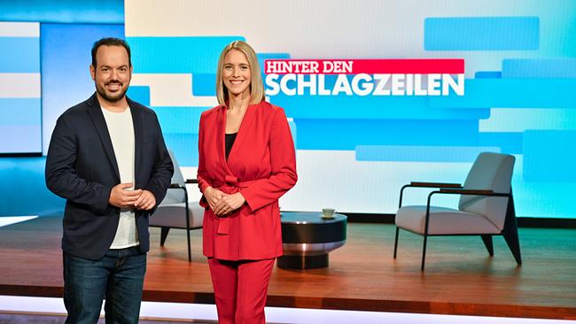 © Thomas Ramstorfer Zwei Moderatoren stehen in einem TV-Studio vor dem Schriftzug ‚Hinter den Schlagzeilen
