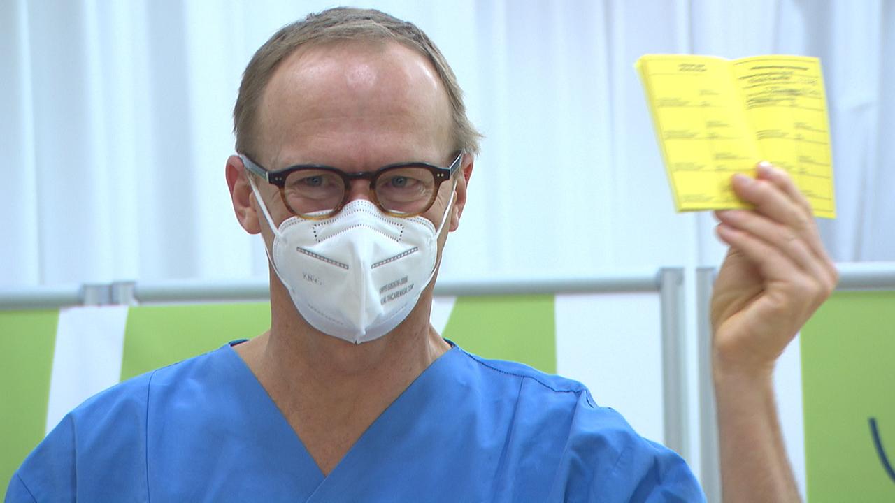 © ORF/Bernhard Werany Infektiologe Christoph Wenisch hält einen Impfpass in die Höhe.