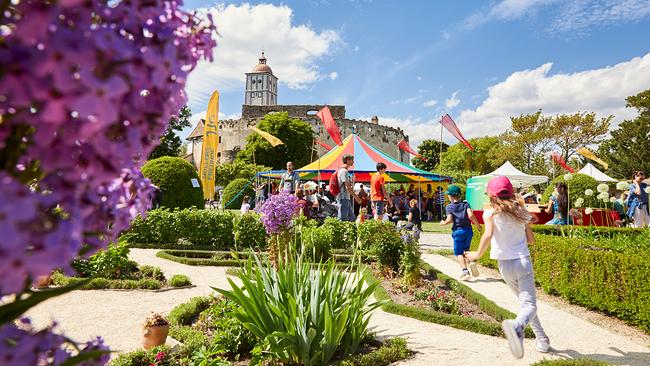 © Rupert Pessl Im Schlossgarten der Schallaburg findet das Familienfest statt. Ein Kind läuft einen Weg entlang Richtung Partyzelt. Die Sonne scheint.