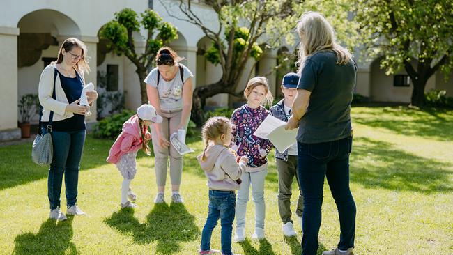 Eine Gruppe mit Kindern und Erwachsenen stehen im sonnigen Garten und studieren die Schatzkarten.