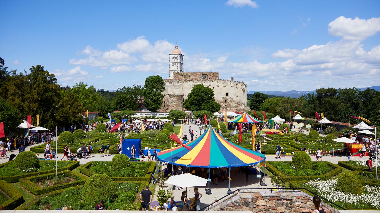 © Rupert Pessl Im Schlossgarten der Schallaburg wird das Familienfest gefeiert. Zu sehen sind viele bunte Zeltdächer, Fahnen und Gäste. Im Hintergrund steht die Schallaburg.