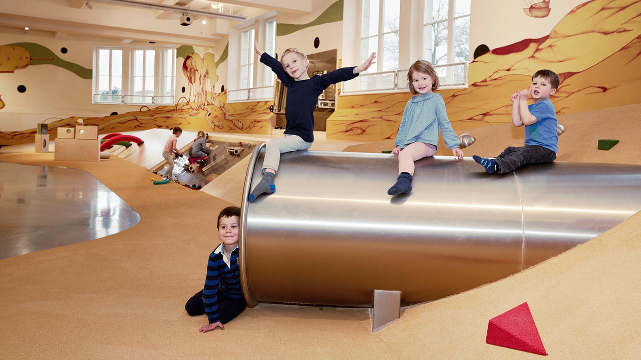 Im Bild: Vier Kinder befinden sich im Technischen Museum und sitzen vor und auf einer Röhrenrutsche.
