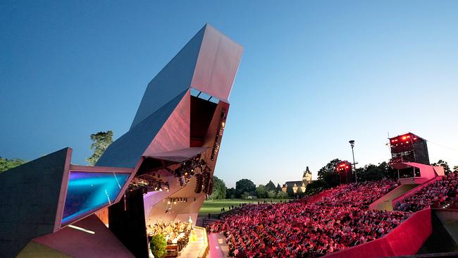 © ORF/Roman Zach-Kiesling Der Wolkenturm Grafenegg, eine moderne Freiluftbühne mit markanter Architektur, ist bei Abendlicht voll besetzt, während die Sommernachtsgala vor großem Publikum unter freiem Himmel stattfindet.