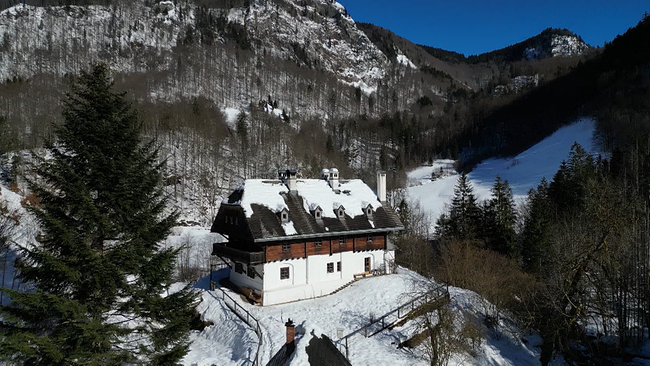 Ein schneebedecktes Forsthaus, eigebettet in die bergige Landschaft des Nationalparks Kalkalpen