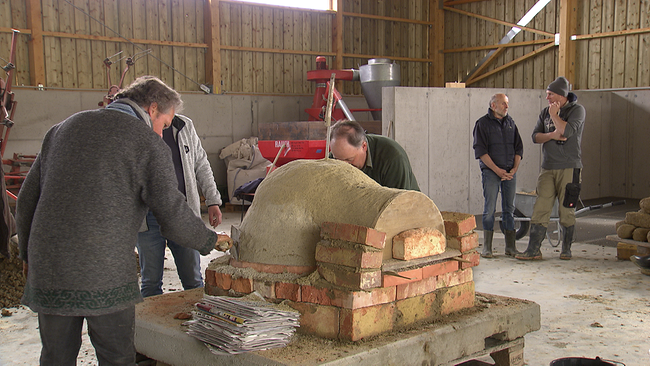 Mehrere Personen arbeiten am Aufbau eines Lehmofens. 