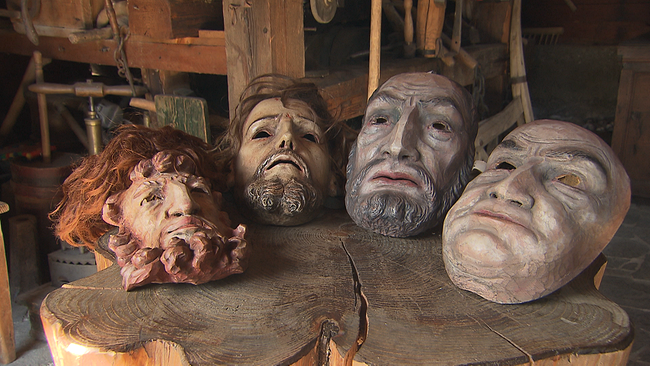 Vier kunstvolle, handgeschnitzte, alte Holzmasken präsentiert auf einem Holztisch