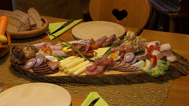 Reichlich bedecktes Holzbrett mit regionalen Wurst und Wildfleischwaren, Käse und selbstgebackenem Brot