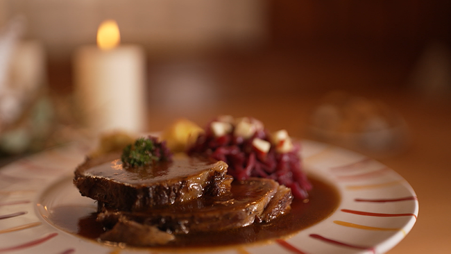 © ORF NÖ festlich angereichtete Tafel mit einem Stück Rinderbraten, Prinzesskartoffel und Rotkraut auf einem Teller