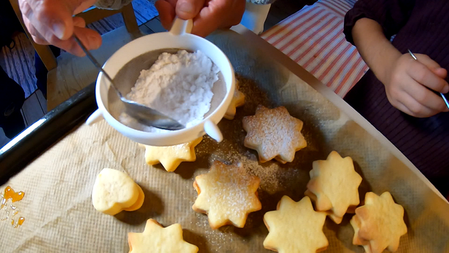 Sternkekse werden mit Staubzucker bestreut, Blick von oben