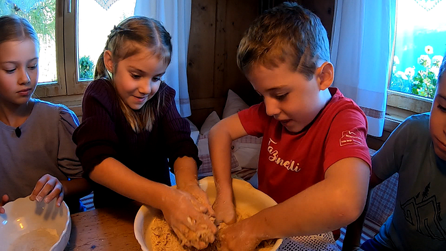 3 Kinder mit ihren Händen in Teigschüsseln beim Keksebacken