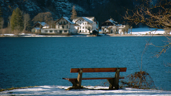 Hallstätter See im Winter mit Schnee am Ufer, Holzbank im Vordergrund