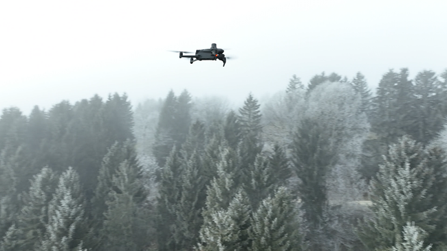 Drohne fliegt über schneebedecktem Wald