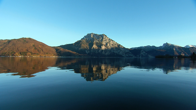 Traunsee mit Bergen und Spiegelung der Berge im See, bei blauem Himmel