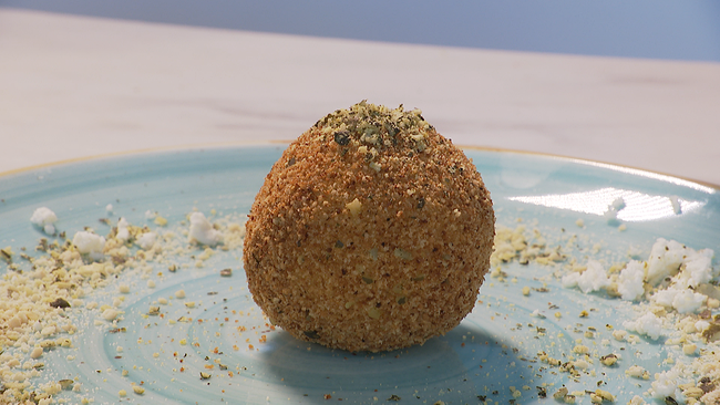 Ein paniertes Knödel liegt auf einem Teller