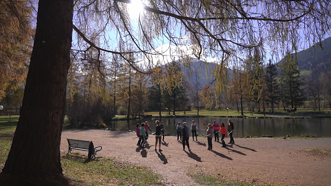 Gruppe von Menschen trainiert vor See in Bergkulisse