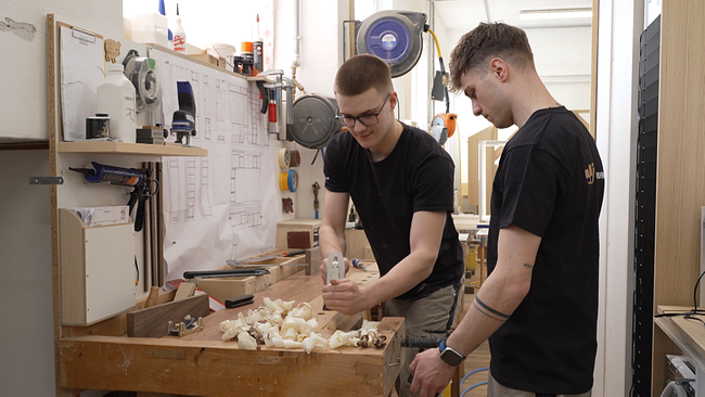 Zwei junge Tischler beim Hobeln