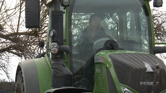 Bäuerin fährt mit dem Traktor