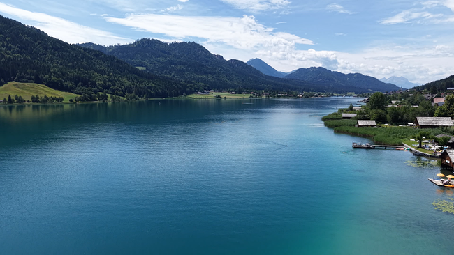 © ORF NÖ Eine blaustrahlende Seefläche mit Bergmassiven im Hintergrund. An den Ufern sind Dörfer, Gemeinden zu erkennen.