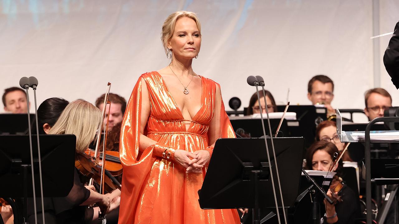 © Katharina Schiffl Elina Garanca in einem orangen Kleid auf der Bühne umgeben vom Orchestra.