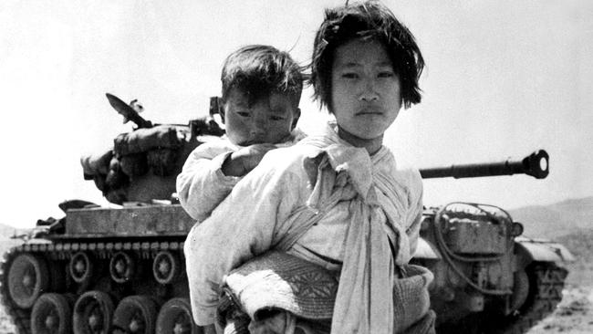 Mit ihrem Bruder auf dem Rücken stapft ein koreanisches Mädchen müde an einem M-26-Panzer vorbei in Haengju, Korea. 9. Juni 1951.