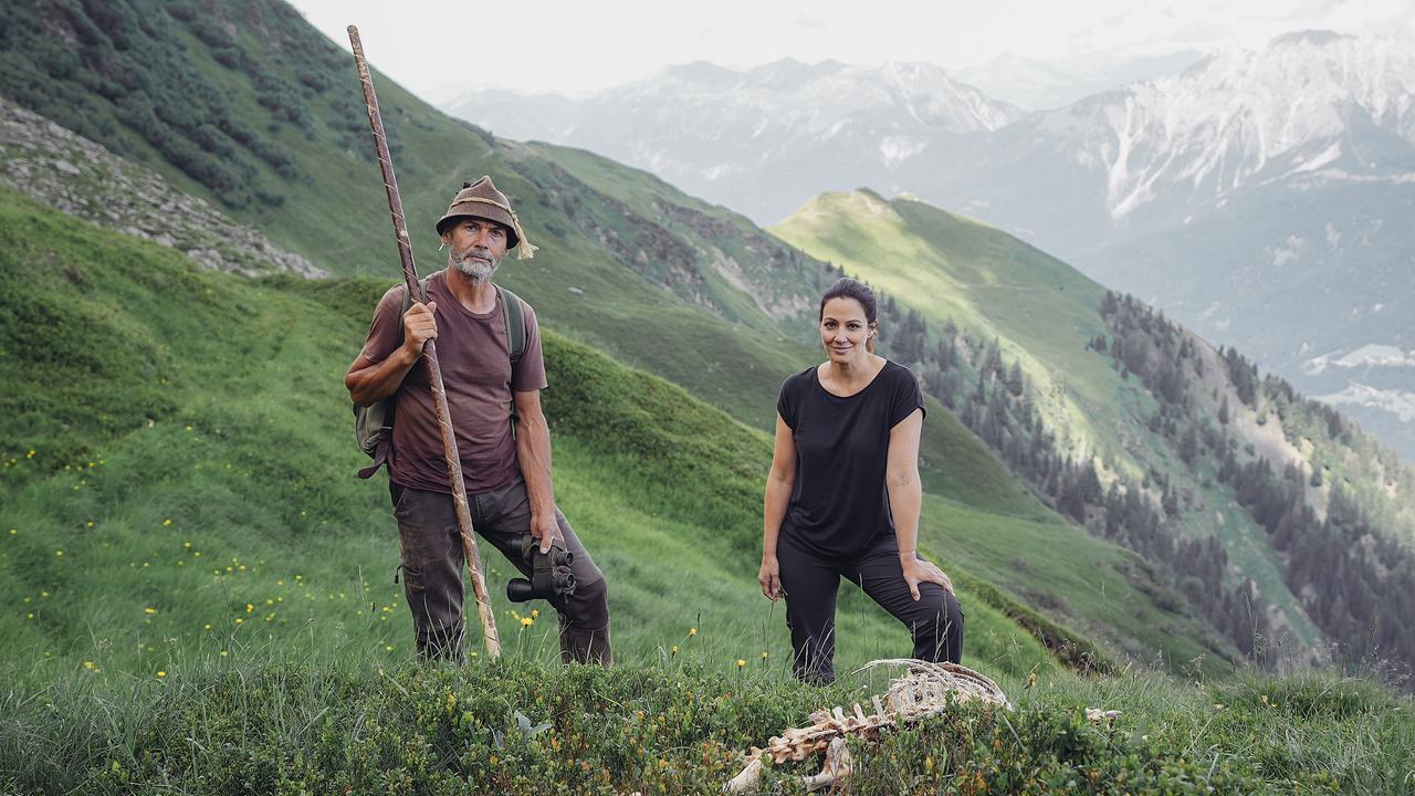 Schaf-Bio-Almbauer Martin Martin steht mit Lisa Gadenstätter auf einer Alm mit wunderschönem Bergpanorama im Hintergrund