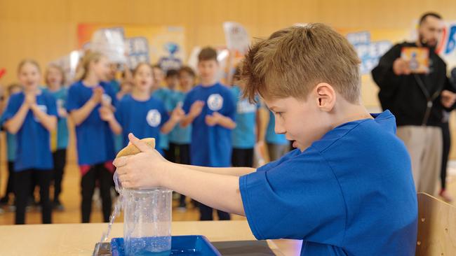© ORF/ungefiltert Ein Volksschüler wringt mit einem Schwamm Wasser in einem Gefäß aus