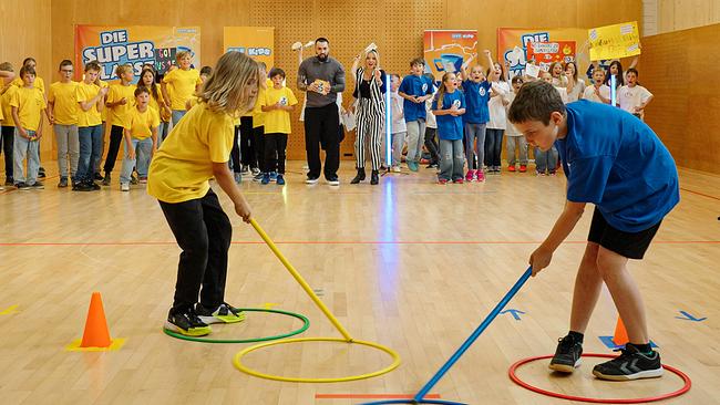 Zwei Kinder stehen in bunten Gymnastikreifen und halten einen Stab in ihren Händen.