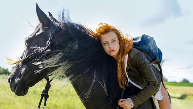 Ein Mädchen mit roten Haaren sitzt auf einem schwarzen Pferd.